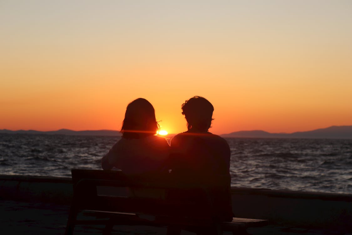 silhouette couple sitting on bench