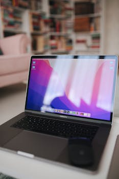A sleek laptop displaying a colorful screen in a cozy living room with bookshelves in the background.
