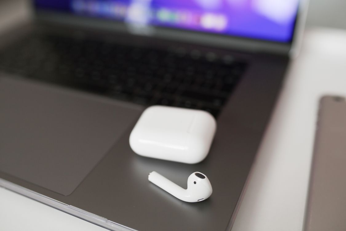White wireless earbuds resting on the keyboard area of an open laptop