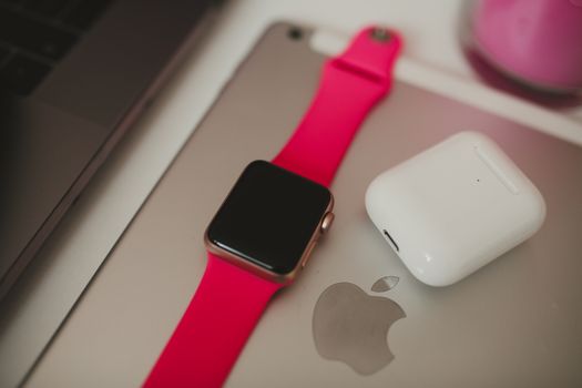 Flat lay composition of smart gadgets including a watch and earbuds on a device.