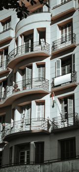 Contemporary urban building featuring stylish curved balconies and grid windows.