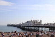 在英国布莱顿码头，人们正享受着阳光明媚的海滩，呈现出一派热闹景象