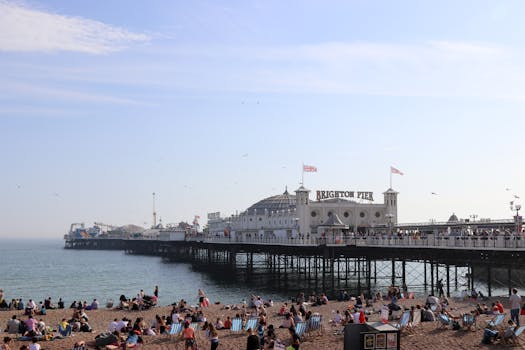 在英国布莱顿码头，人们正享受着阳光明媚的海滩，呈现出一派热闹景象