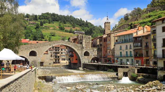 Picturesque view of the historic stone bridge and charming village of Camprodon, Spain on a sunny day.