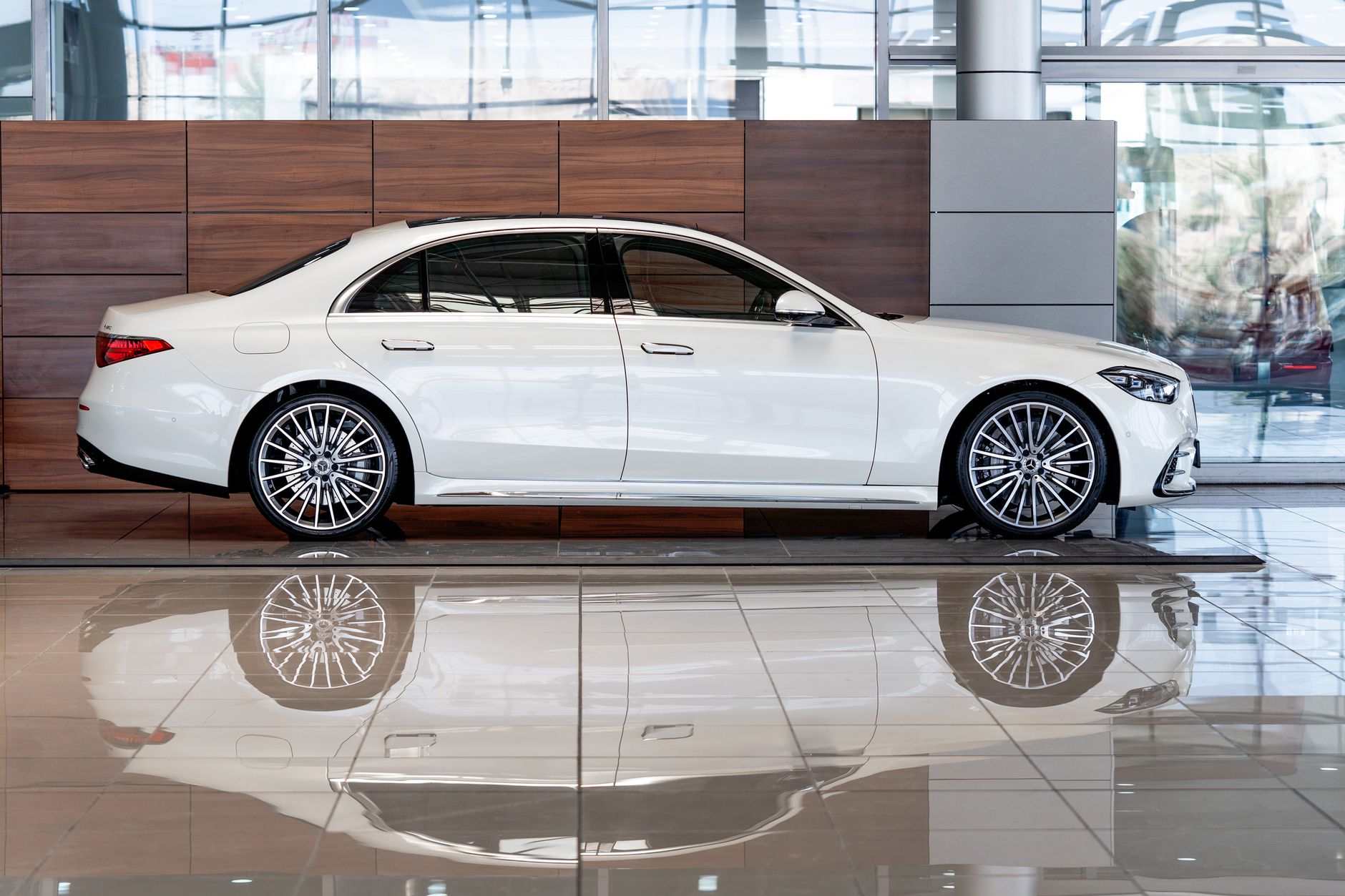A sleek white luxury car displayed inside a modern showroom in Dubai, UAE.