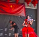 文化节期间，一位才华横溢的小提琴家身穿鲜艳的红色连衣裙在舞台上表演
