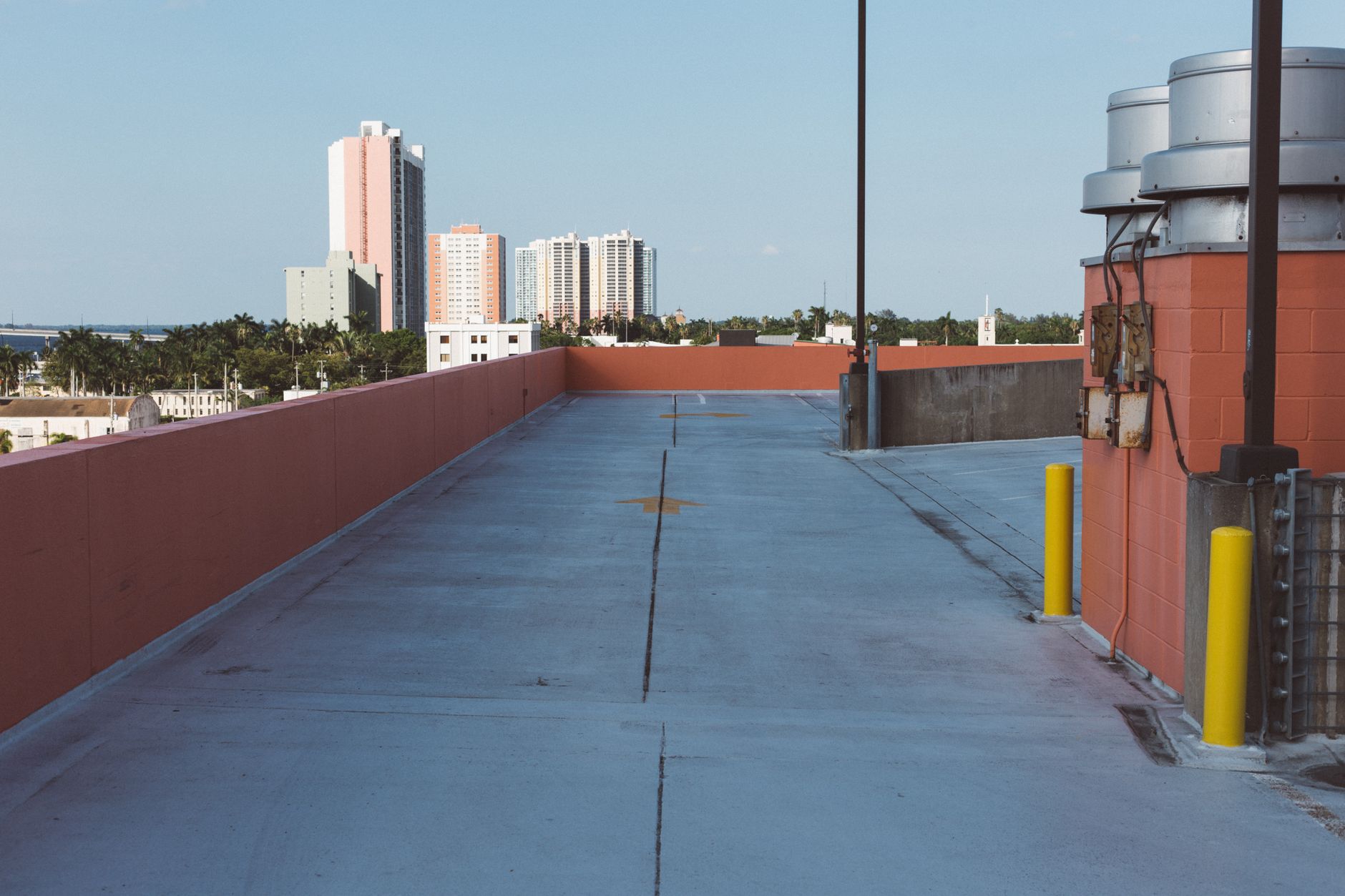 Expansive urban rooftop scene with distant city buildings under a clear blue sky.