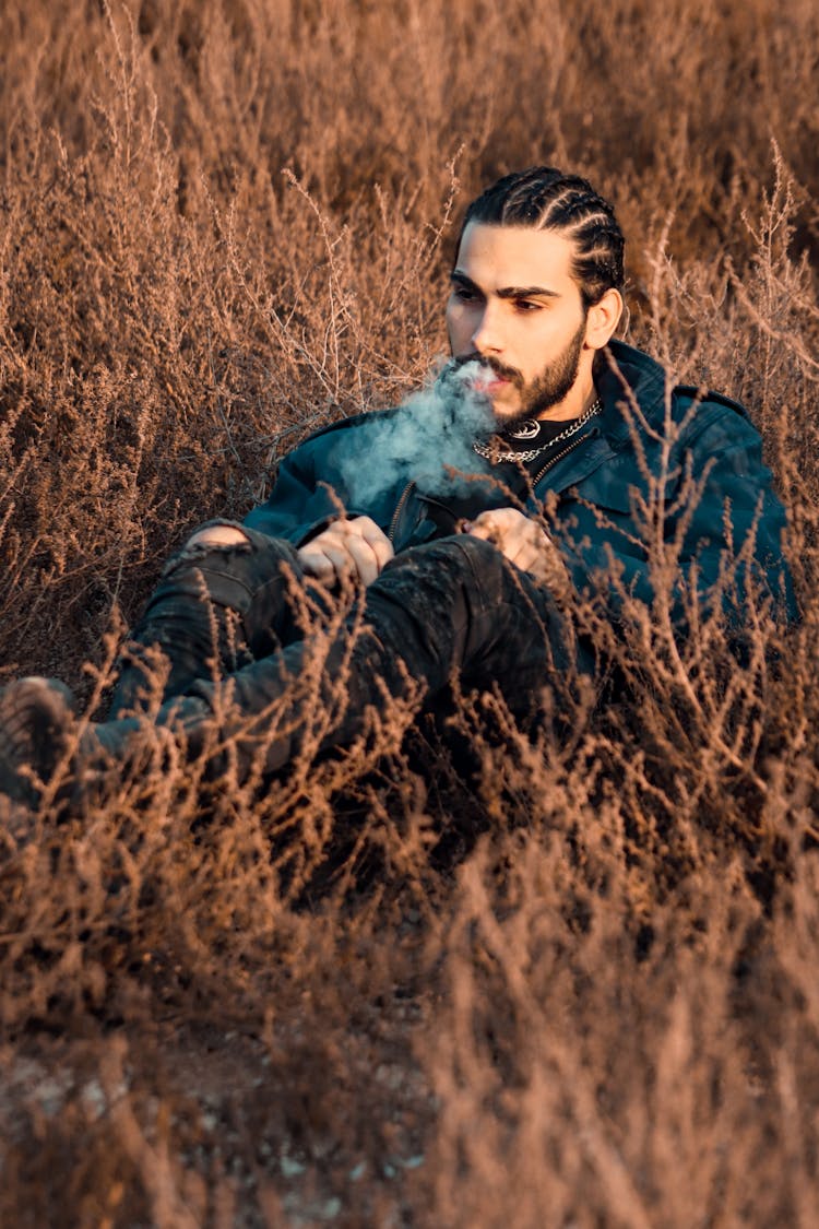 A Man Vaping Sitting On Grass