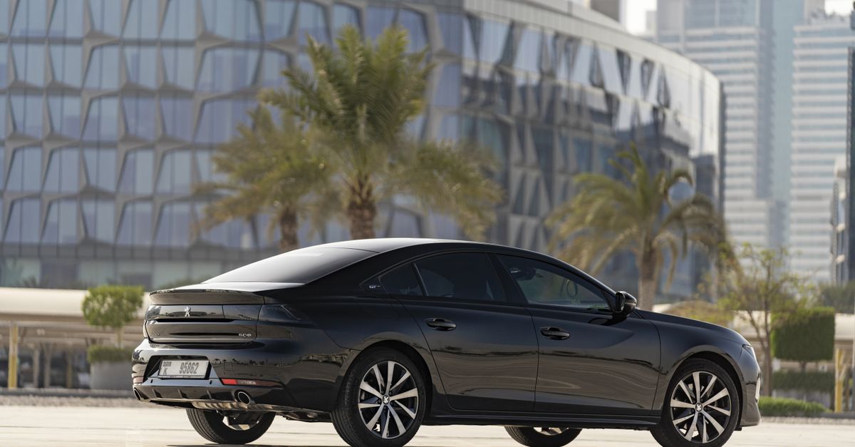 A sleek white VinFast electric SUV stands prominently inside a modern, minimalist Dubai showroom with bright lighting.