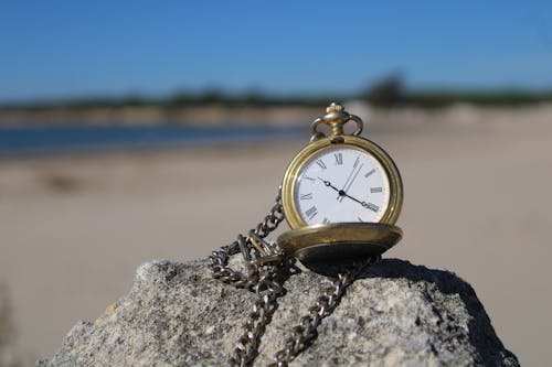Free Gold Pocket Watch on Top of a Rock Stock Photo