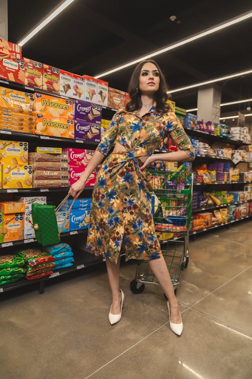 Free Woman in Blue and Yellow Floral Dress Standing on Grocery Store Stock Photo