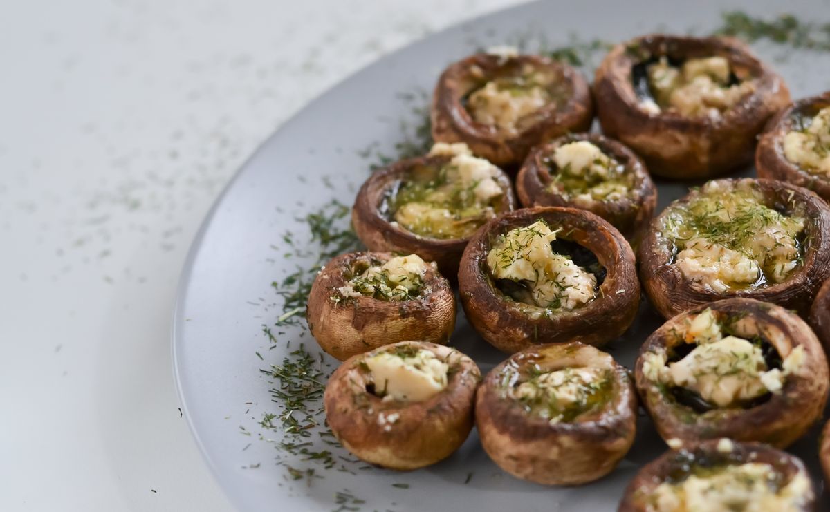Cream cheese stuffed mushrooms garnished with herbs on a plate