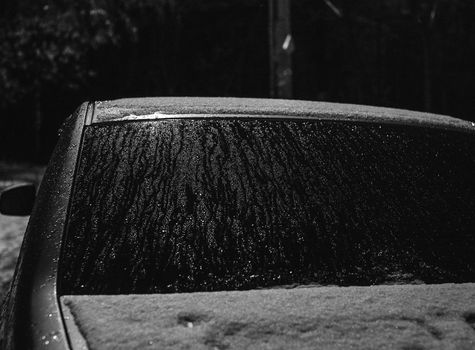 Black and white photo of a snow-covered car windshield, creating a winter atmosphere.