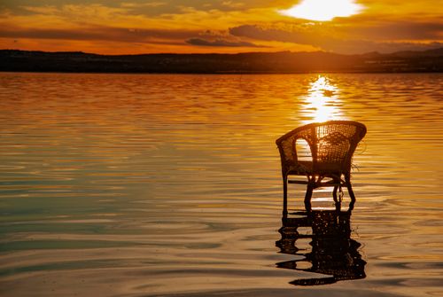 Free Rattan armchair reflected in the tranquil waters during a Torrevieja sunset. Stock Photo