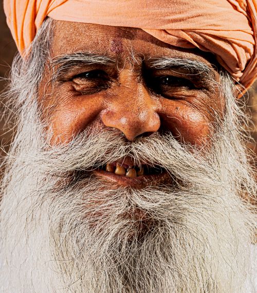 Free Close-up of a smiling elderly man wearing a turban, showcasing a warm and friendly expression. Stock Photo