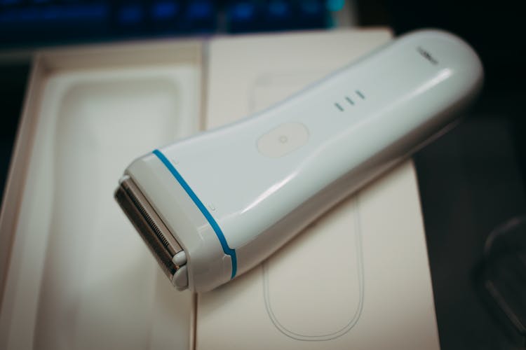 A White And Blue Electric Shaver On Box