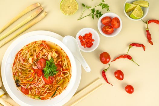 Delicious spicy noodle soup with fresh ingredients like cherry tomatoes and lime slices.
