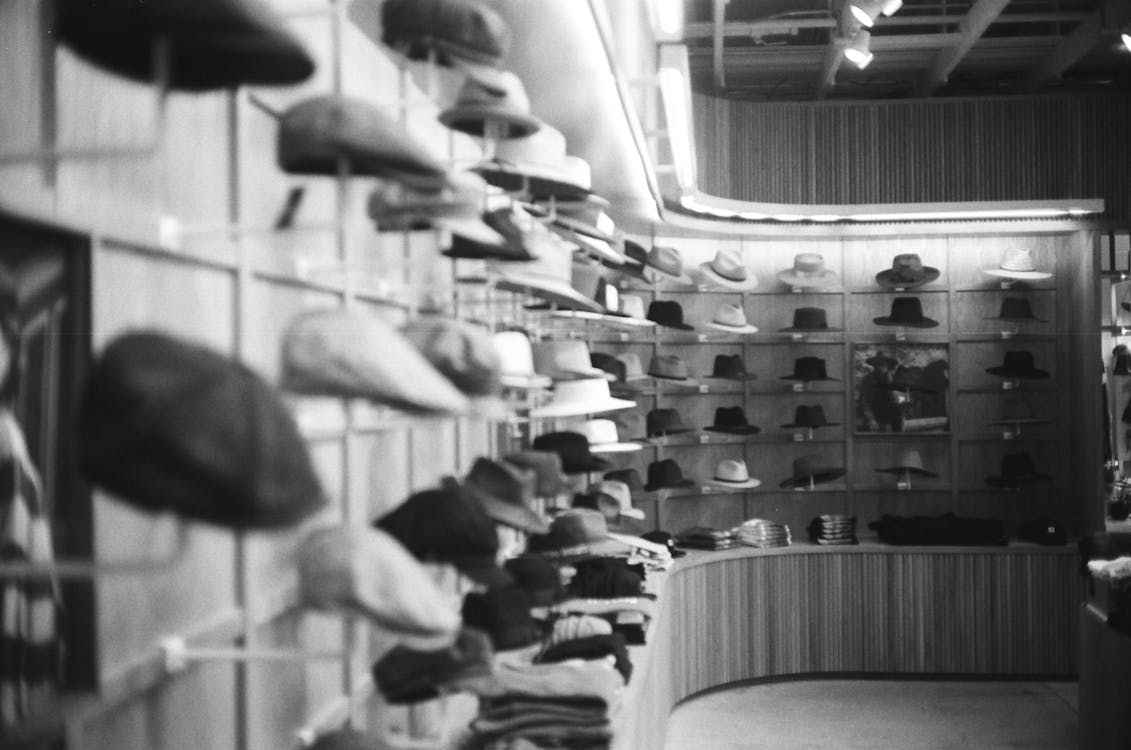 Grayscale Photo of Hats on Shelves