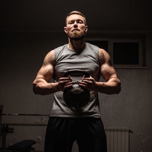Free Strong man with a beard lifting a kettlebell in a gym, showcasing fitness and strength. Stock Photo