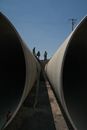 Three Construction Workers Standing on Gravel Near Concrete Pipes