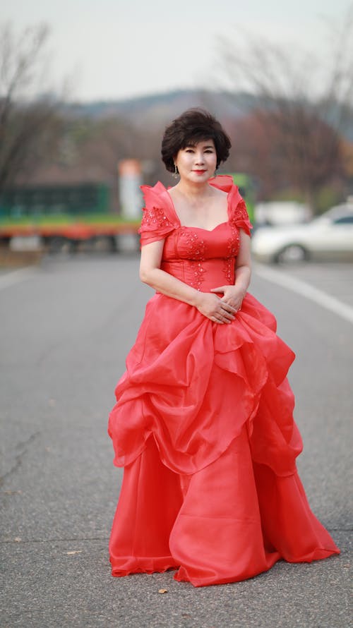 Woman in Red Gown Standing on Road 