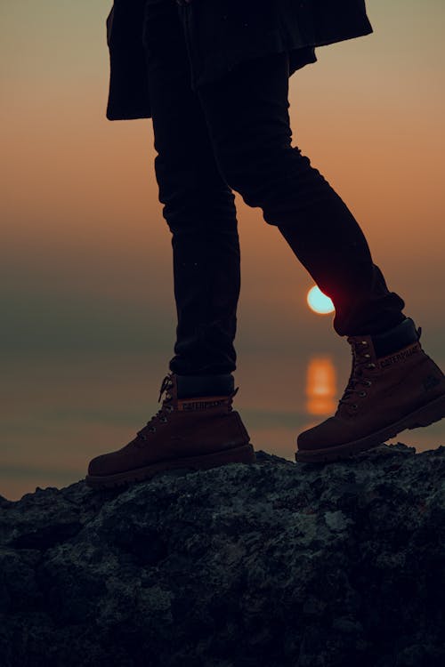 Person Wearing Boots Standing on a Big Rock