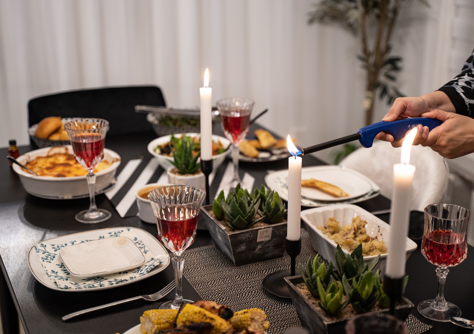 A beautifully set dinner table with candles, wine, and succulent plants creating an elegant and cozy atmosphere.