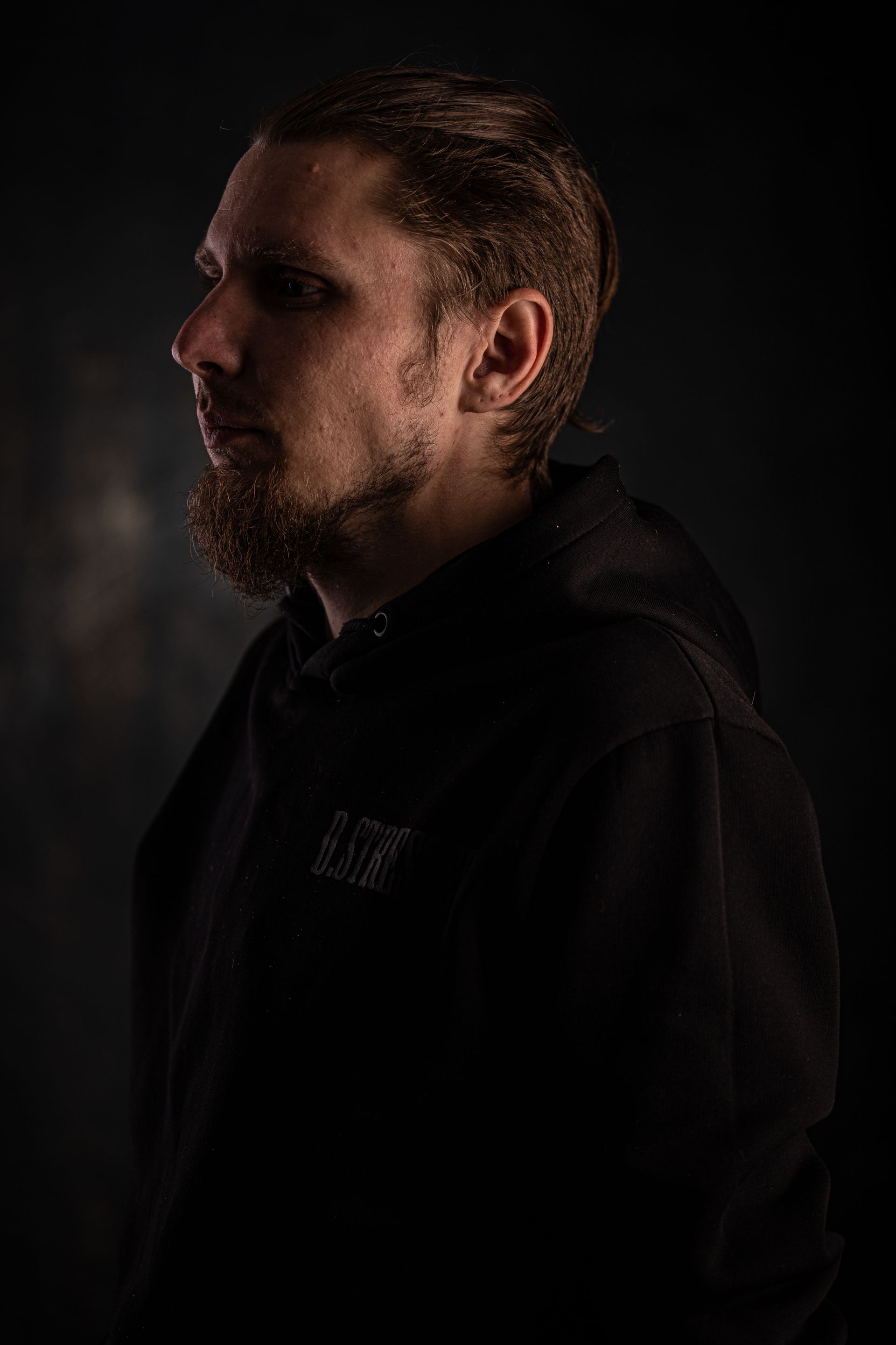 Portrait of a bearded filmmaker lit dramatically on a dark film set
