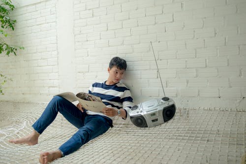 Free Boy Sitting Near Radio Holding White Catalog Stock Photo