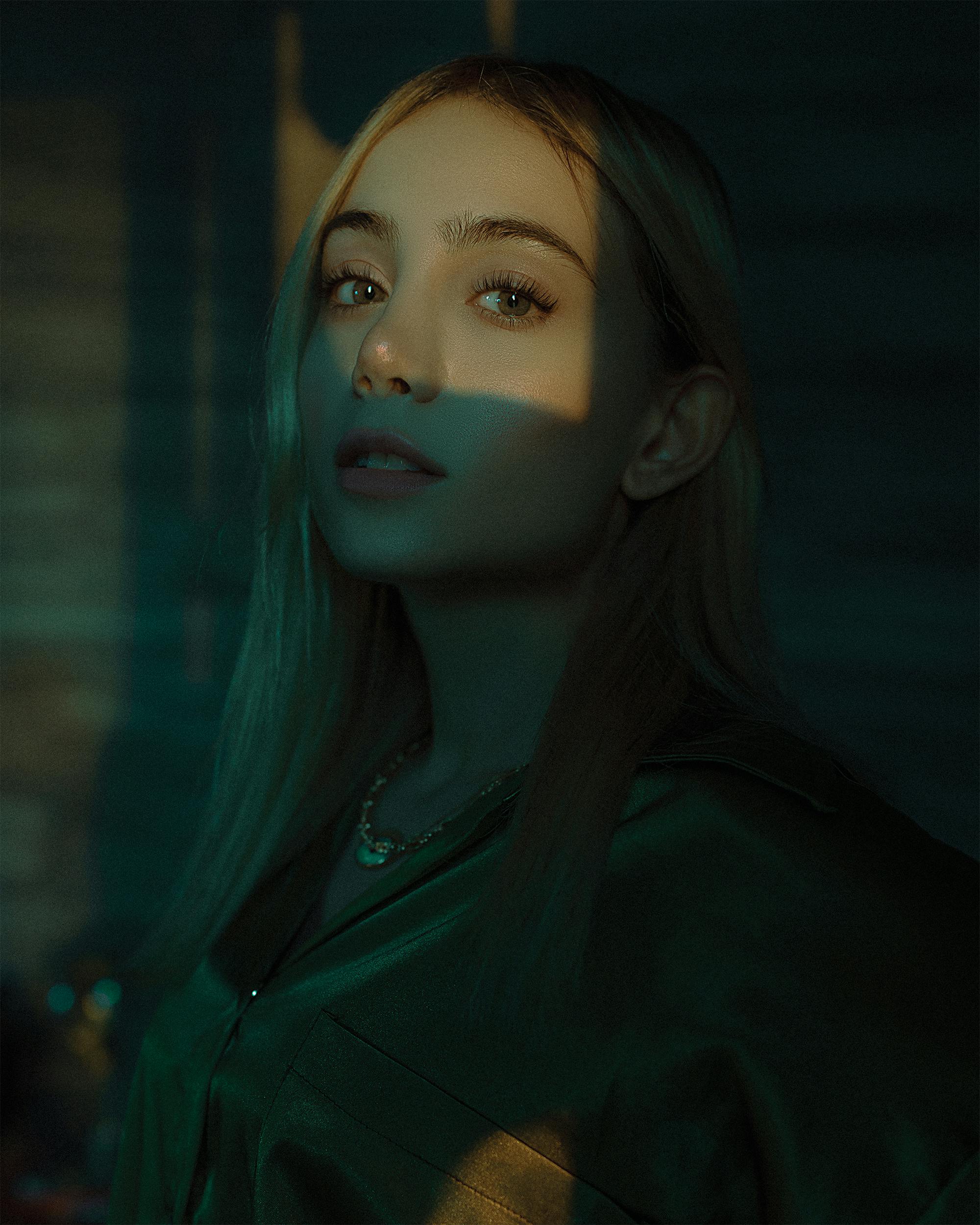 Artistic portrait of a woman in dramatic lighting highlighting face and necklace.