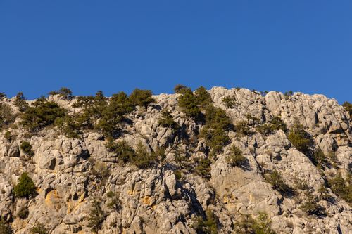 Free Stunning view of a rocky mountain cliff against a clear blue sky, highlighting nature's beauty. Stock Photo