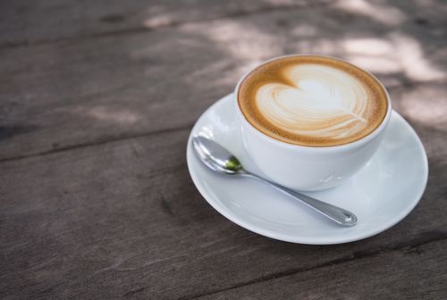 Free A close-up of a creamy latte with heart latte art on a wooden table, perfect for morning caffeine lovers. Stock Photo