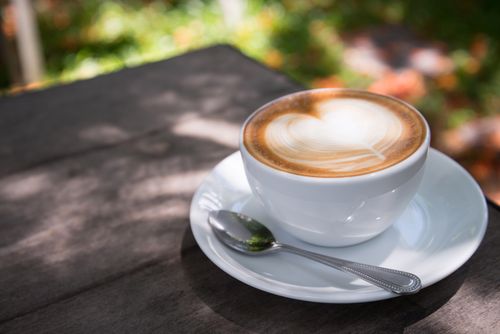 Free A beautifully crafted latte with heart art on a wooden table outdoors. Stock Photo