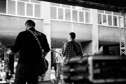 Grayscale Photo of Persons Playing Guitar