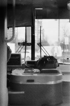 Grayscale photograph of a bus interior showcasing urban life through a windshield.