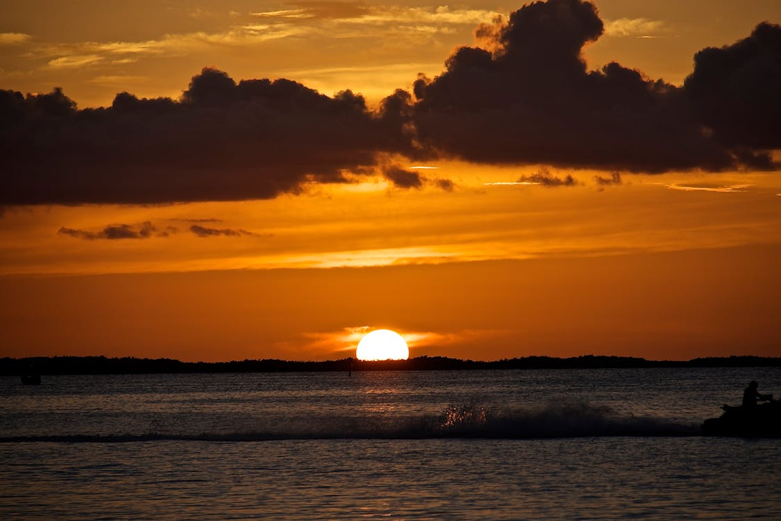 Free Body of Water Under Cloudy Sky during Sunset Stock Photo