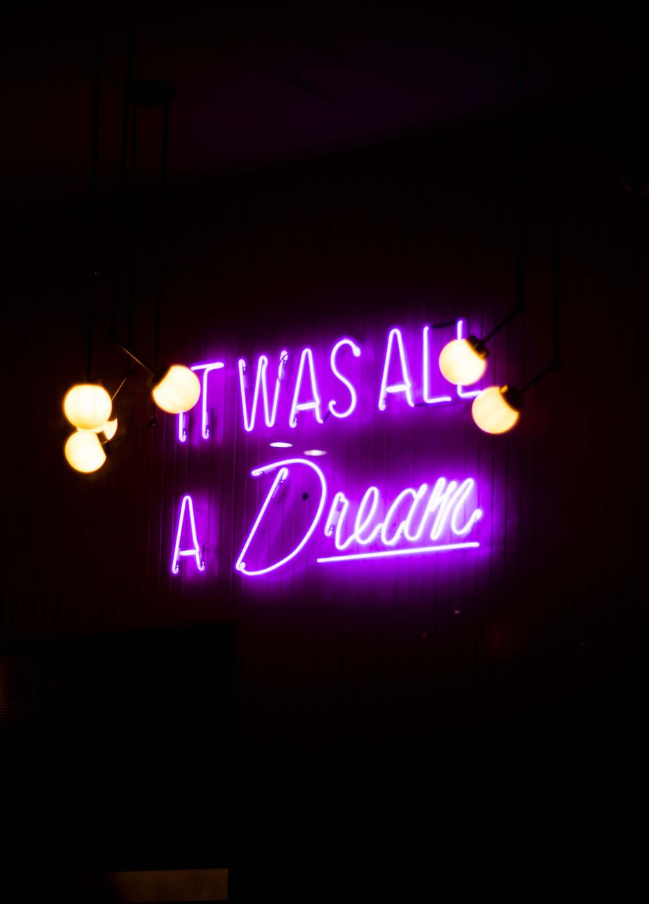 Vibrant neon sign displaying 'It was all a Dream' in a dark setting.