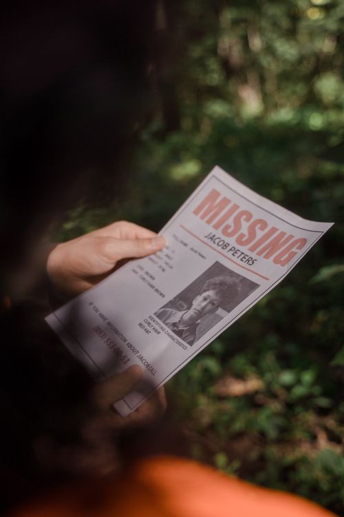 Free Close-up of a missing person poster being held in a forest environment. Stock Photo