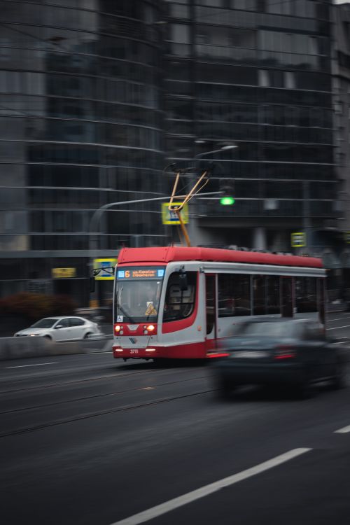 Free Blurred red tram speeding through city streets, capturing urban movement. Stock Photo