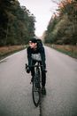Man Cycling in the Middle of the Asphalt Road in the Forest