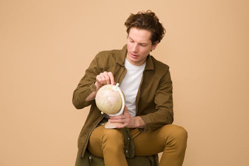 Man Sitting Holding White Desk Globe
