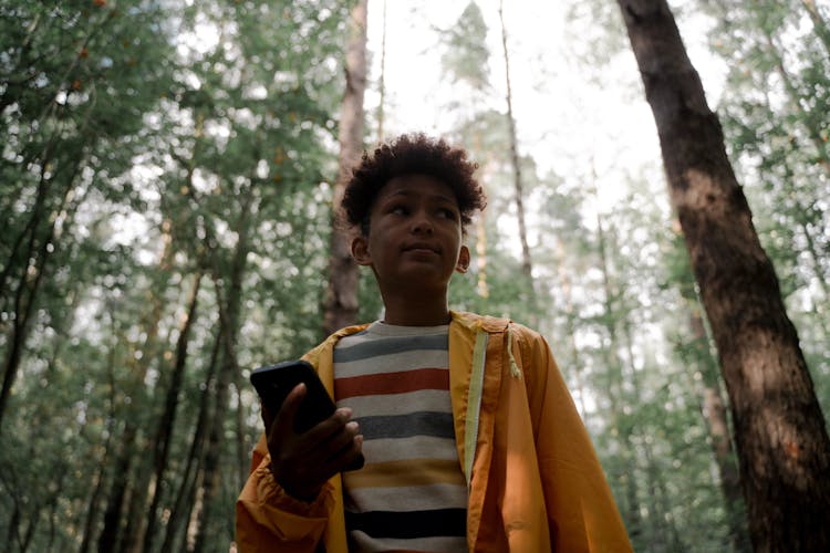 Teenage Boy Holding Smart Phone In Forest