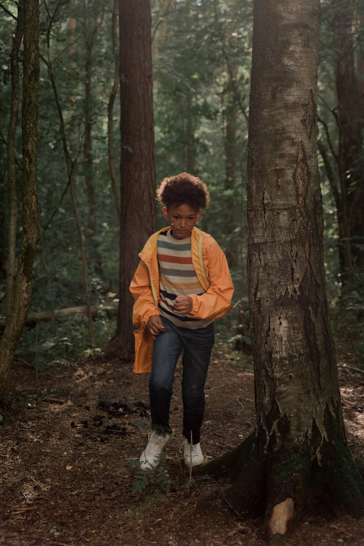 Teenage Boy In Yellow Raincoat Walking In Forest