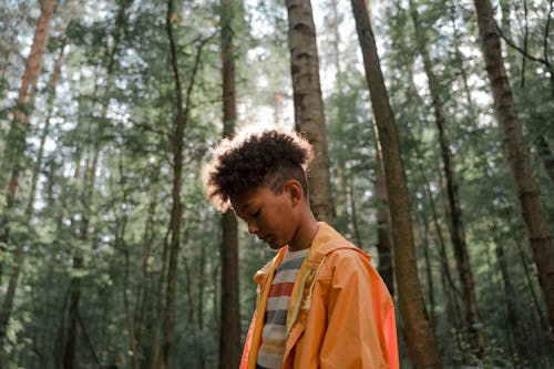 Free Sad Teenage Boy in Yellow Raincoat Standing in Forest Stock Photo