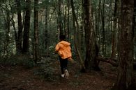 Rear View of Teenage Boy Running in Forest