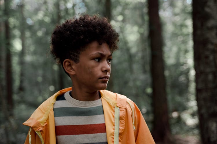 Teenage Boy In Yellow Raincoat In Forest