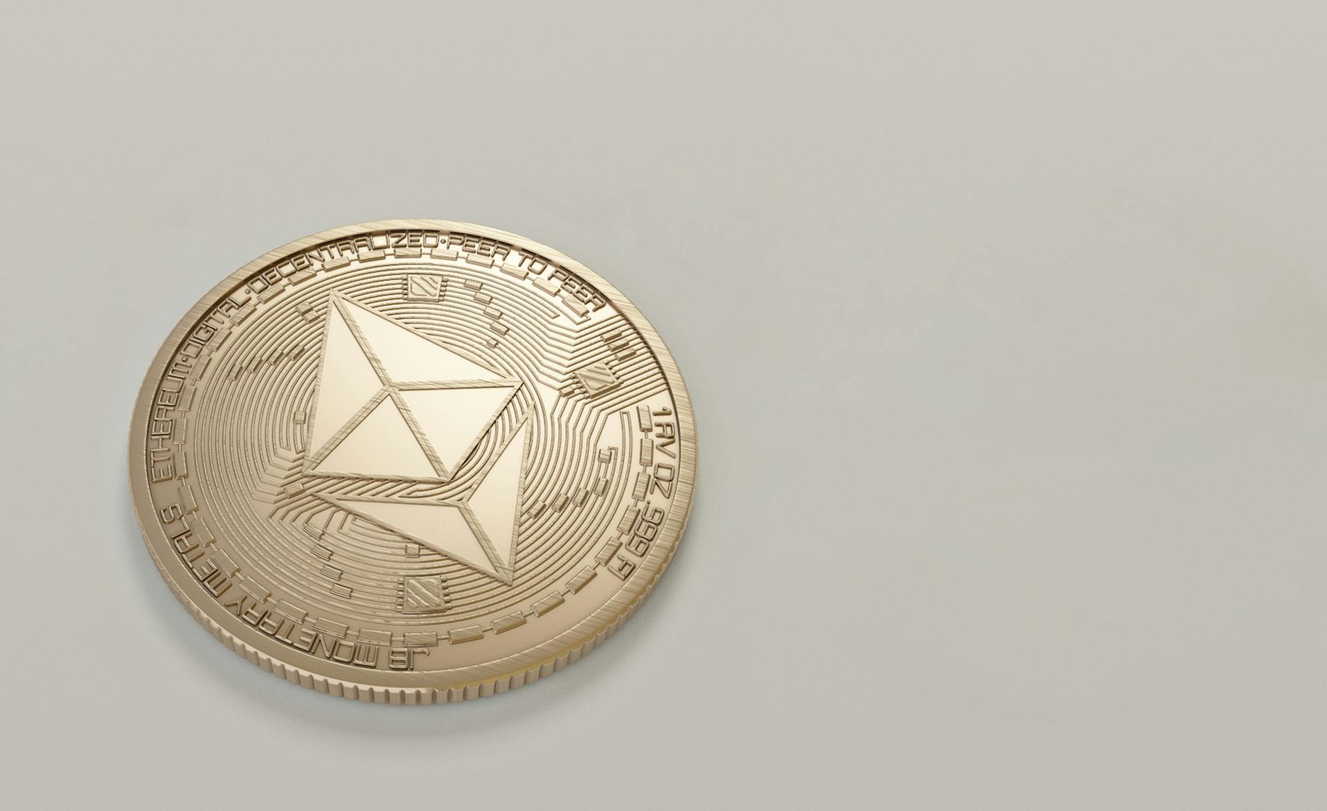 A golden Ethereum coin placed on a neutral light background, symbolizing digital currency.