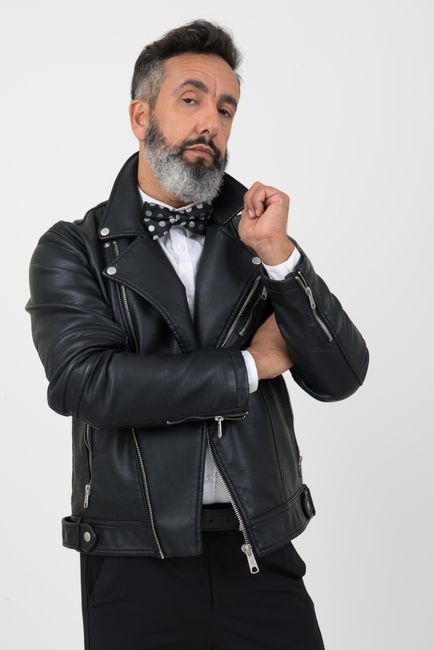 Stylish man posing confidently in a black leather jacket with a bow tie on a white background.