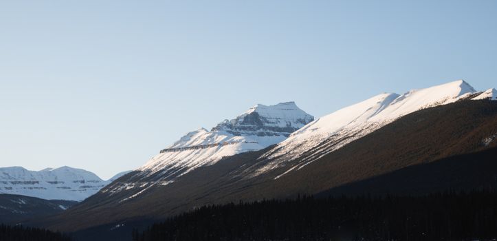 Stunning view of the snow-capped Canadian Rockies under a clear blue sky.