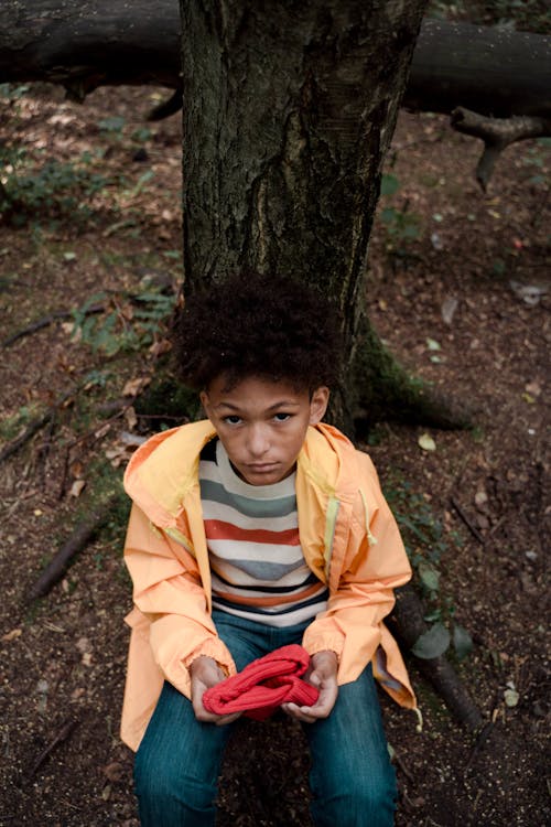 Free Boy with Curly Hair Leaning on Tree Trunk Stock Photo